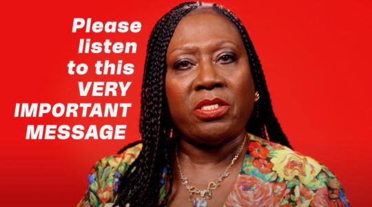 A black lady is facing forwards. Against a bright red background, text in white says 'Please listen to this very important message'