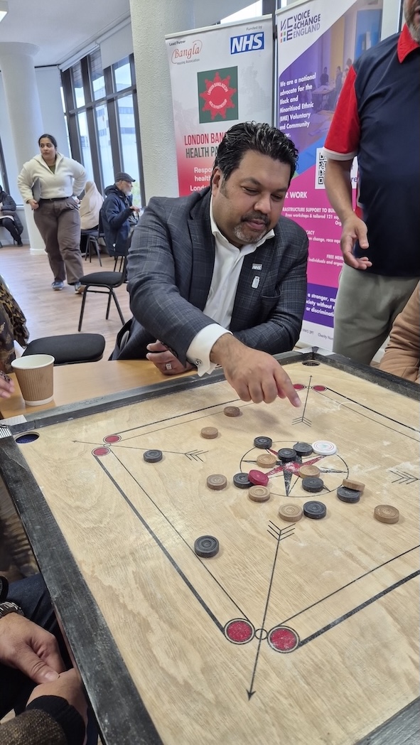 A man is playing a board game called Carrom Board.