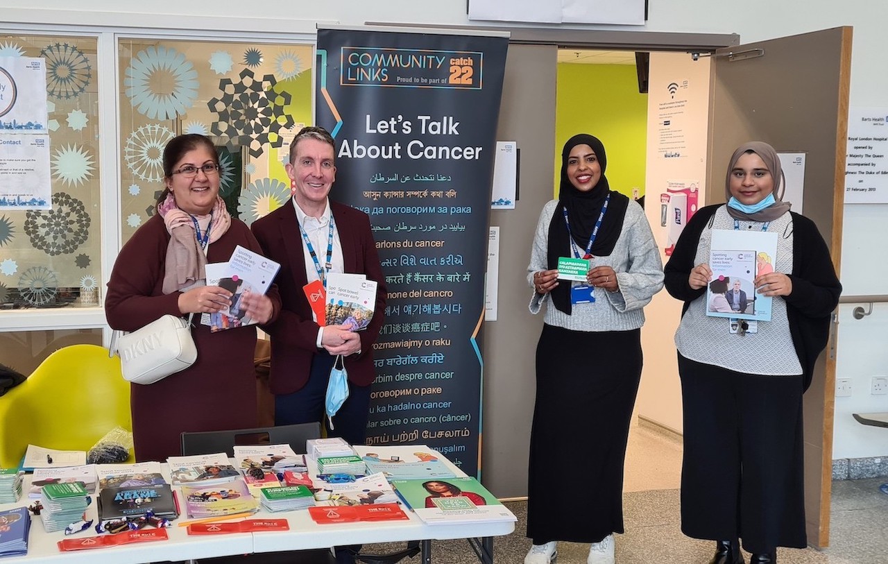 A group of of people are standing in front of a table with cancer information leaflets on it.