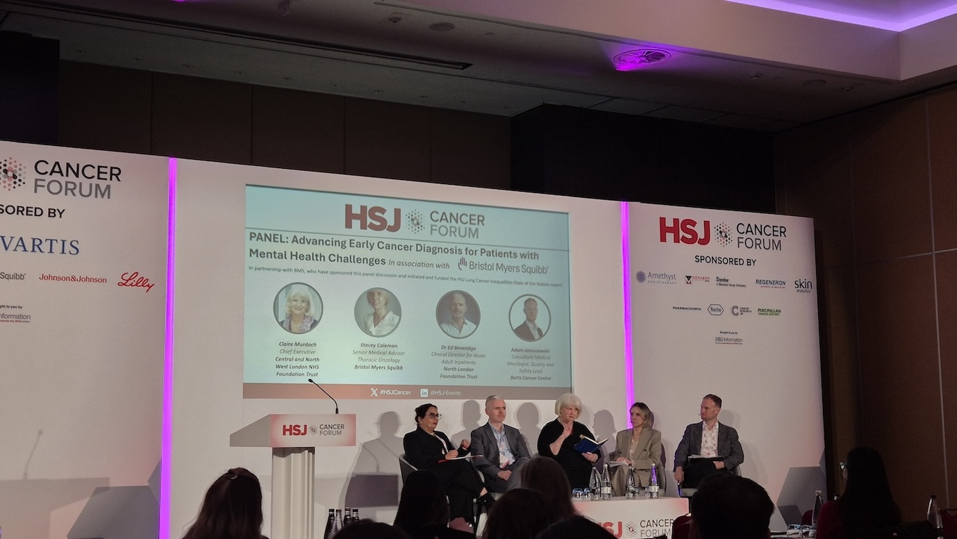 A panel of speakers are sat on a stage in front of a presentation screen which is displaying the words HSJ Cancer Forum.
