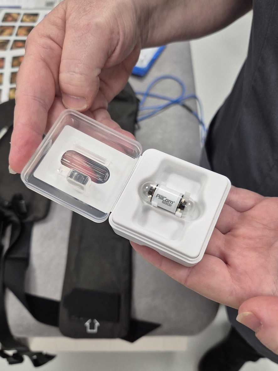 The image is of someone holding a small box with a pill inside it which says PillCam on it