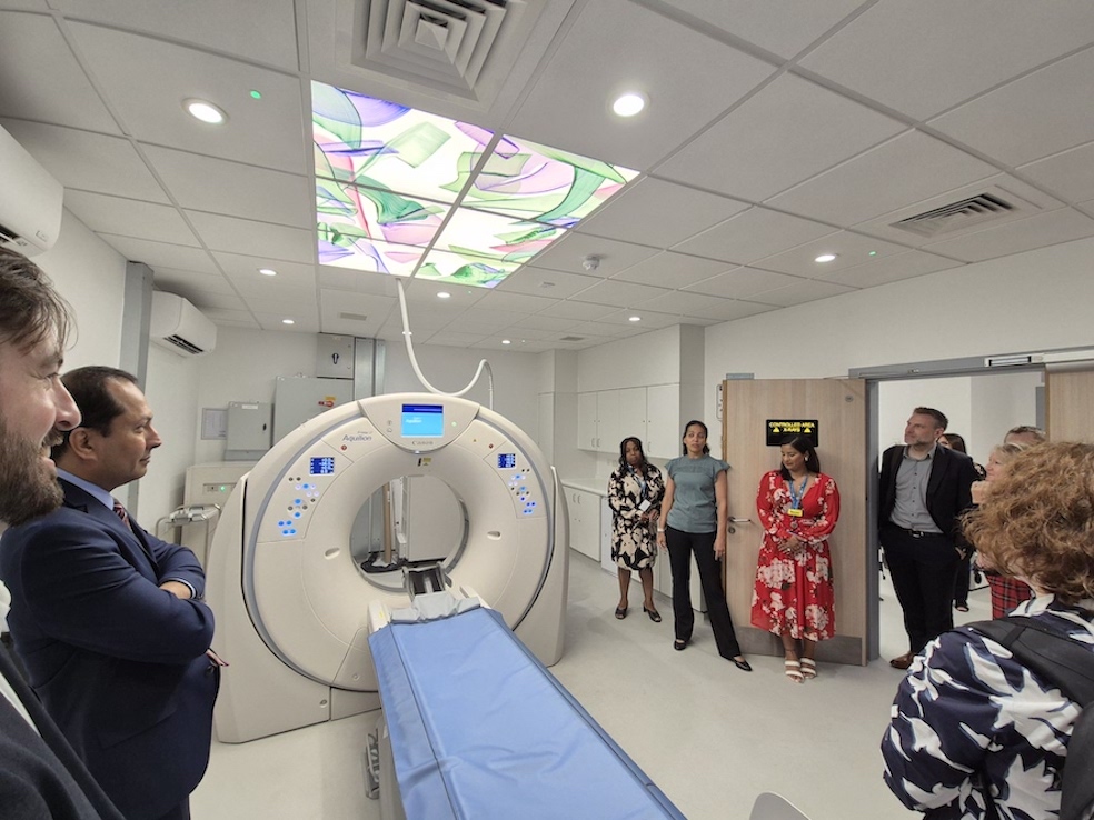 The image is of an MRI scanner with a group of people standing around it