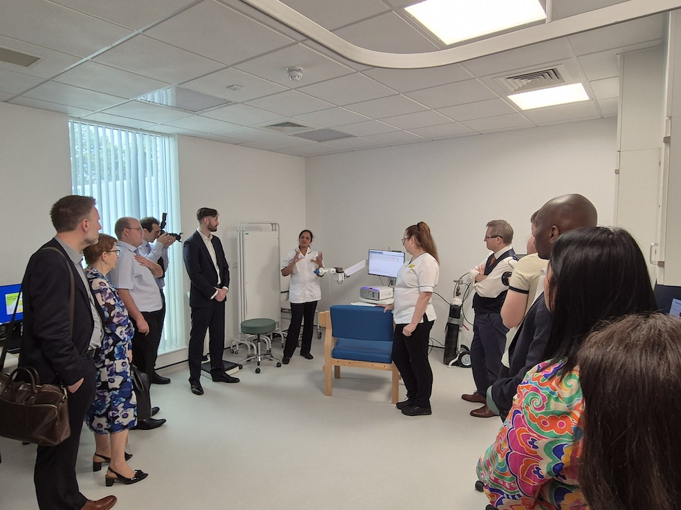 A nurse is demonstrating thee use of a respiratory machine to a group of people standing in a hospital room