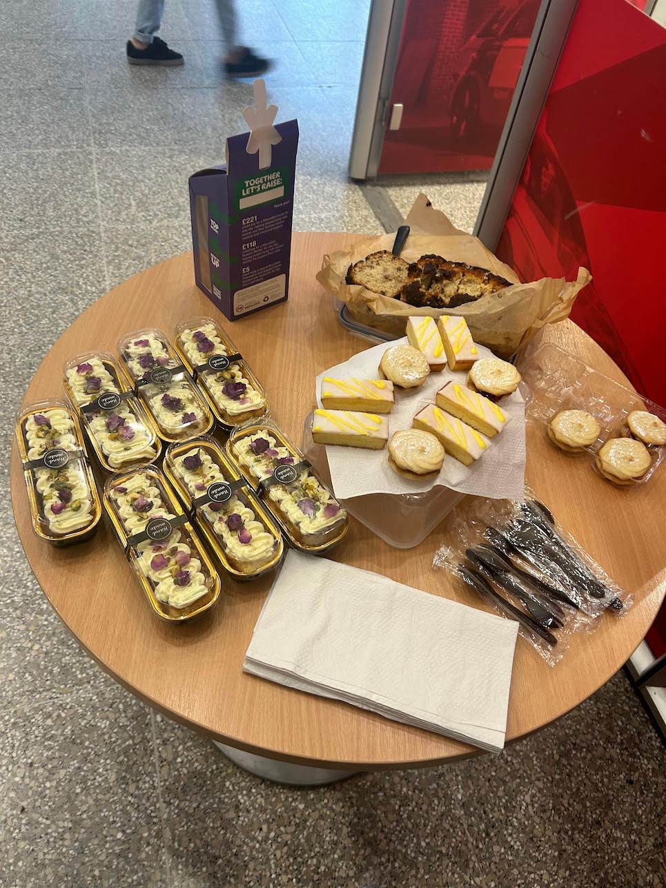 The image is of a small round table which has a selection of cakes on it.