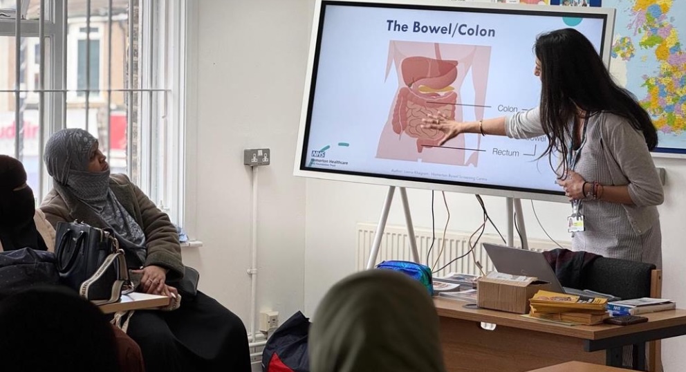 A lady giving a presentation about bowel screening.