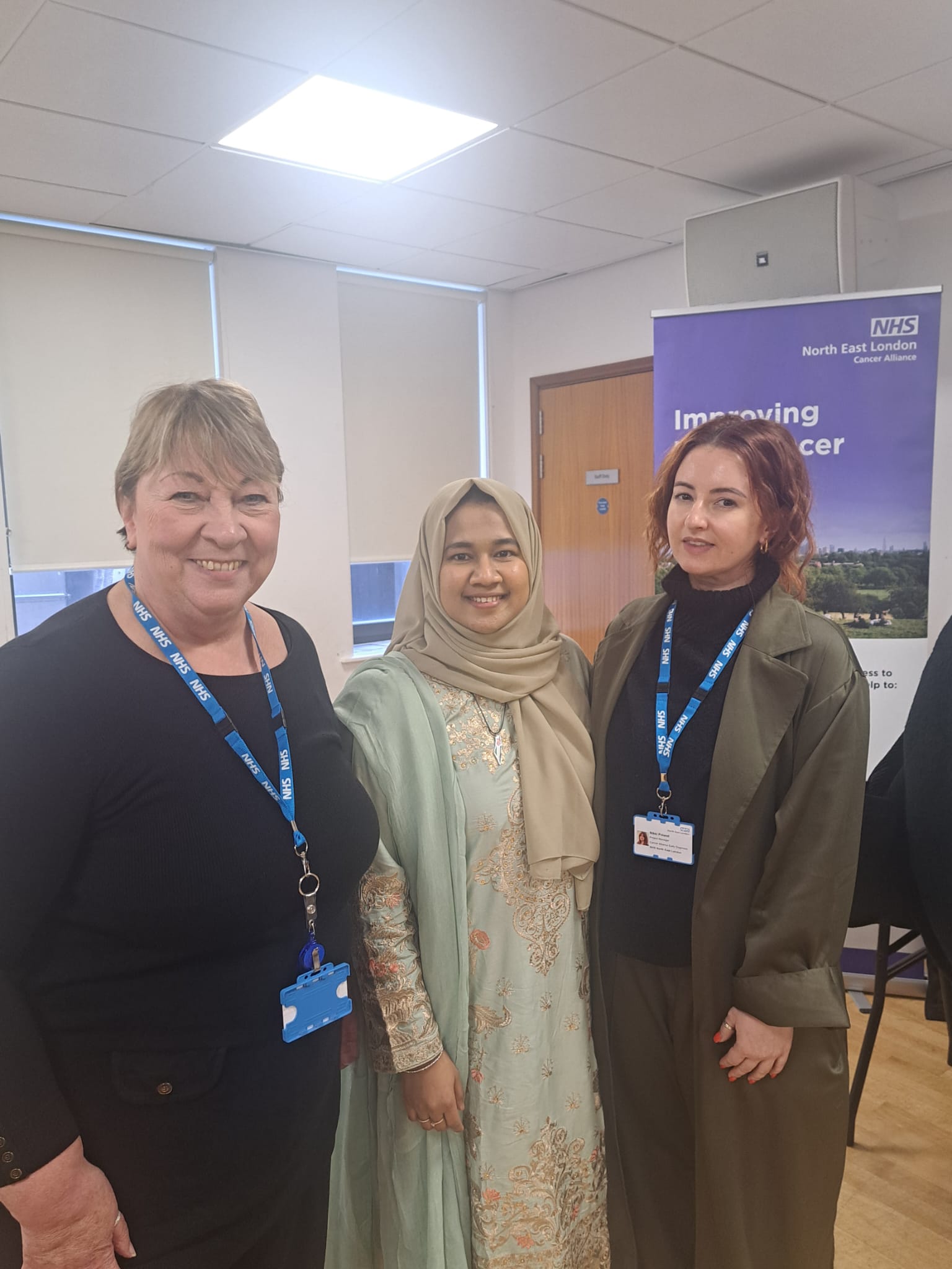 Three women are standing together looking straight ahead at the camera