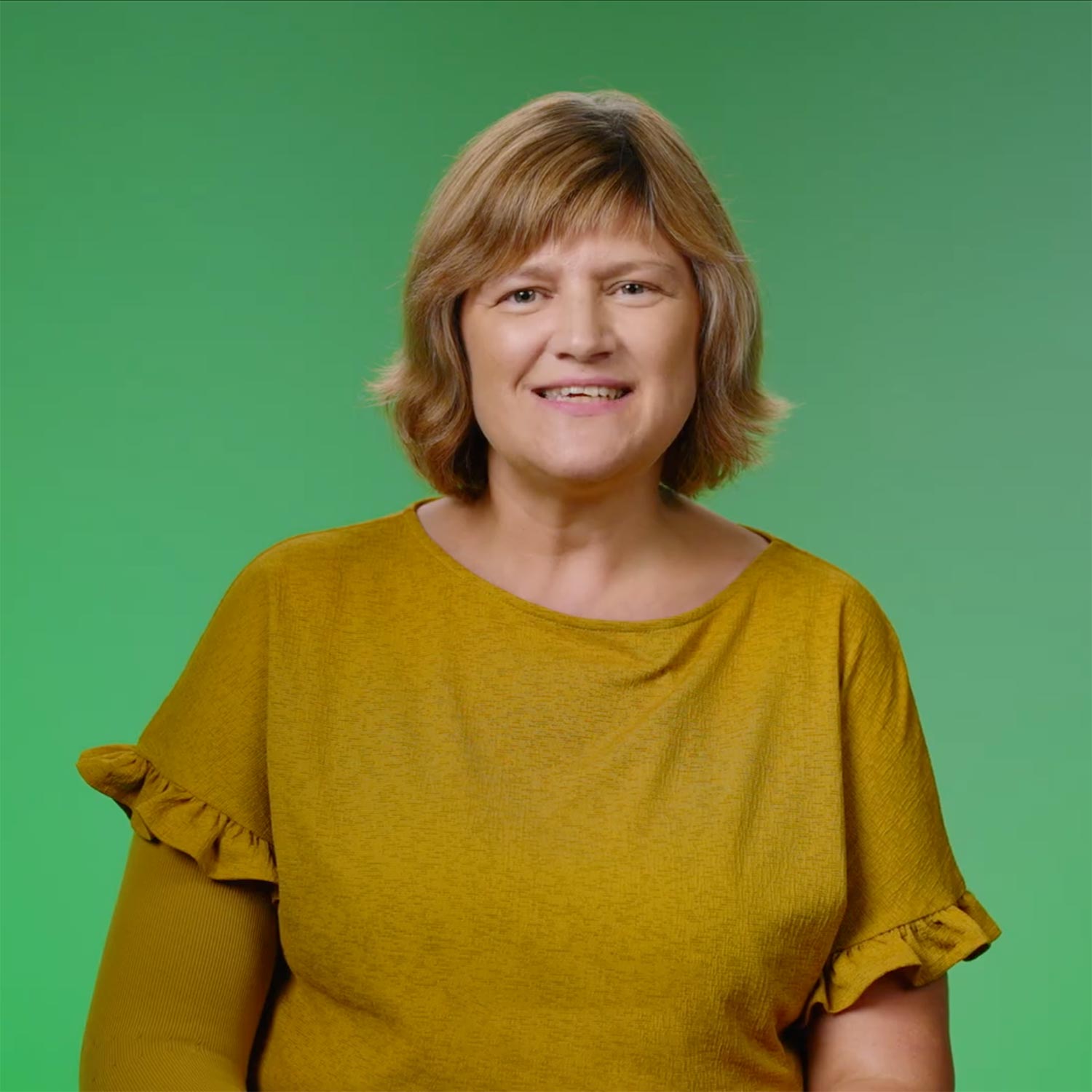 A portrait of a lady looking ahead against a green background.
