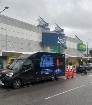 A van with It's Not A Game written on it parked outside a Boots superstore