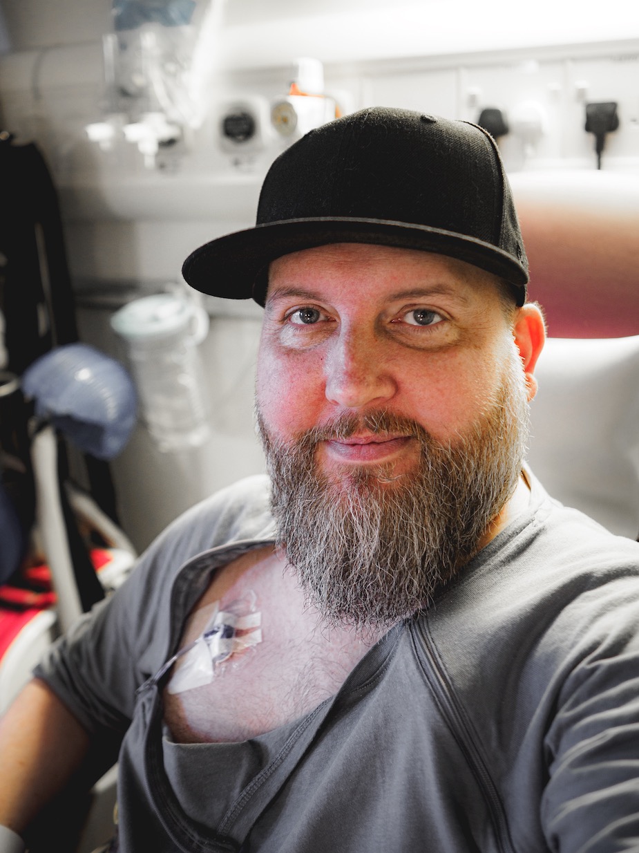 A man is on a hospital bed facing the camera.