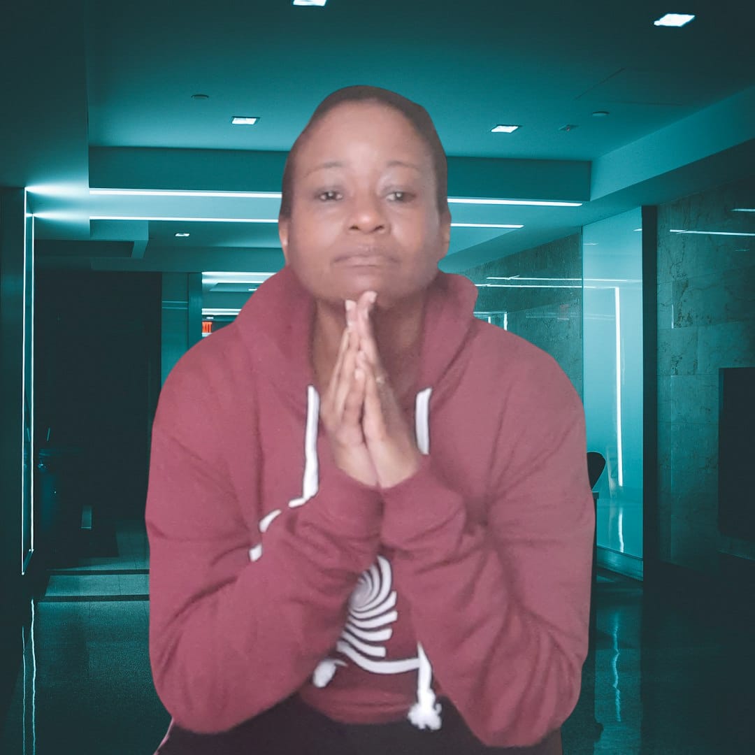 A black female has her chin resting on her hands and is wearing a maroon hooded sweatshirt