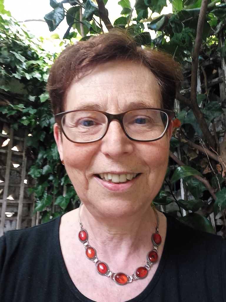 The picture is a close up photograph of a women with glasses looking  in to the camera