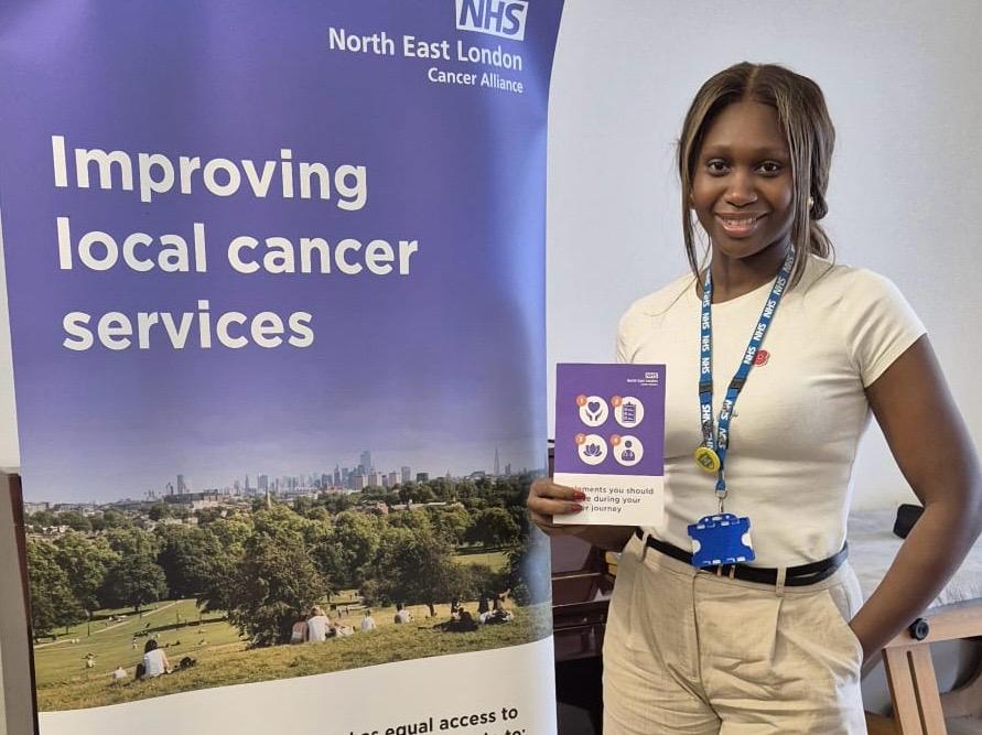 A lady is standing next to a banner which says improving local cancer services on it