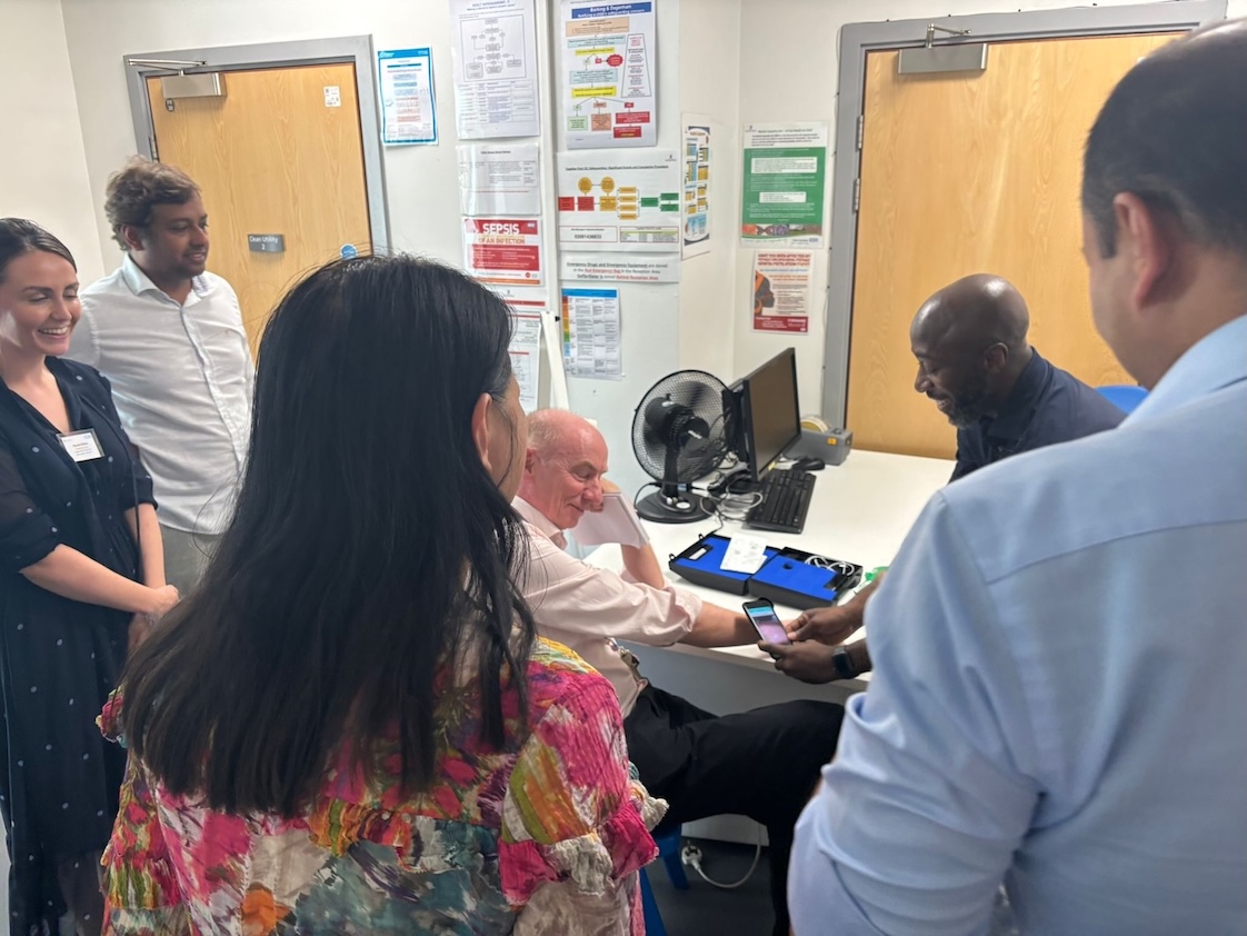 A man is having a section of his skin photographed by a GP using a smart phone