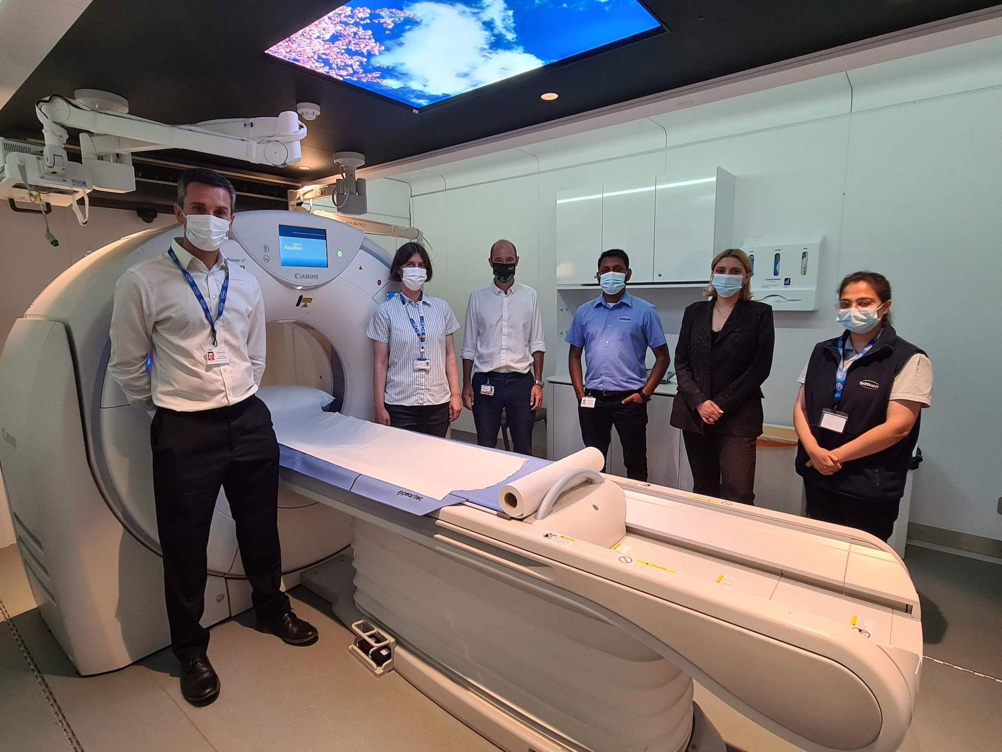 A team of healthcare professionals standing  by a lung scanner
