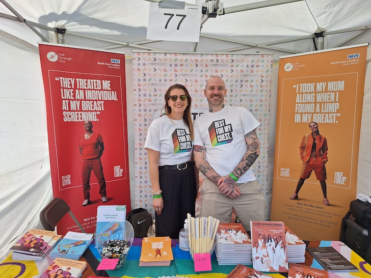 Two people are standing in front of a marketing information stand. It says Best For My Chest on their tshirts