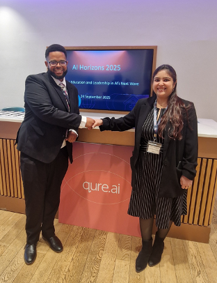 A man and a woman are shaking hands in front of a board which says qure.ai on it.