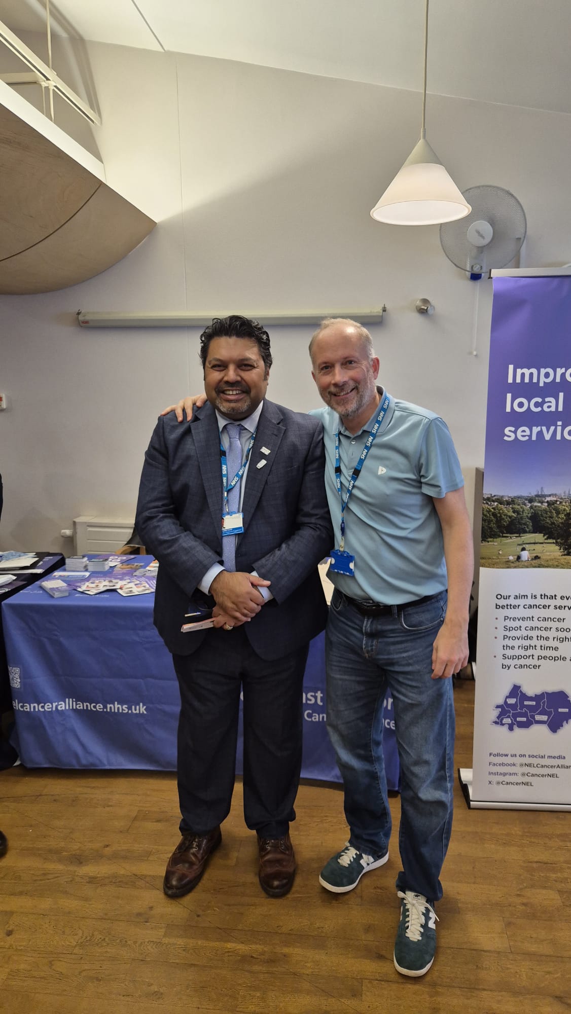 two NHS staff standing in front of the NELCA stand