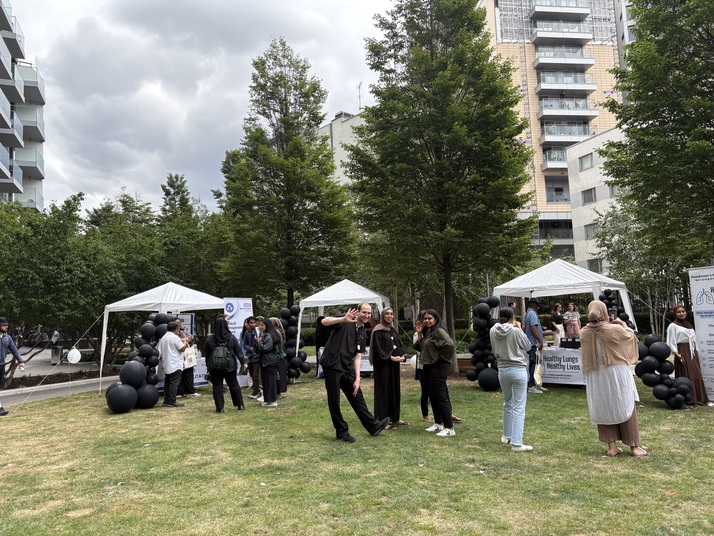 people standing in a communal space with stands sharing informative materials on healthy lungs
