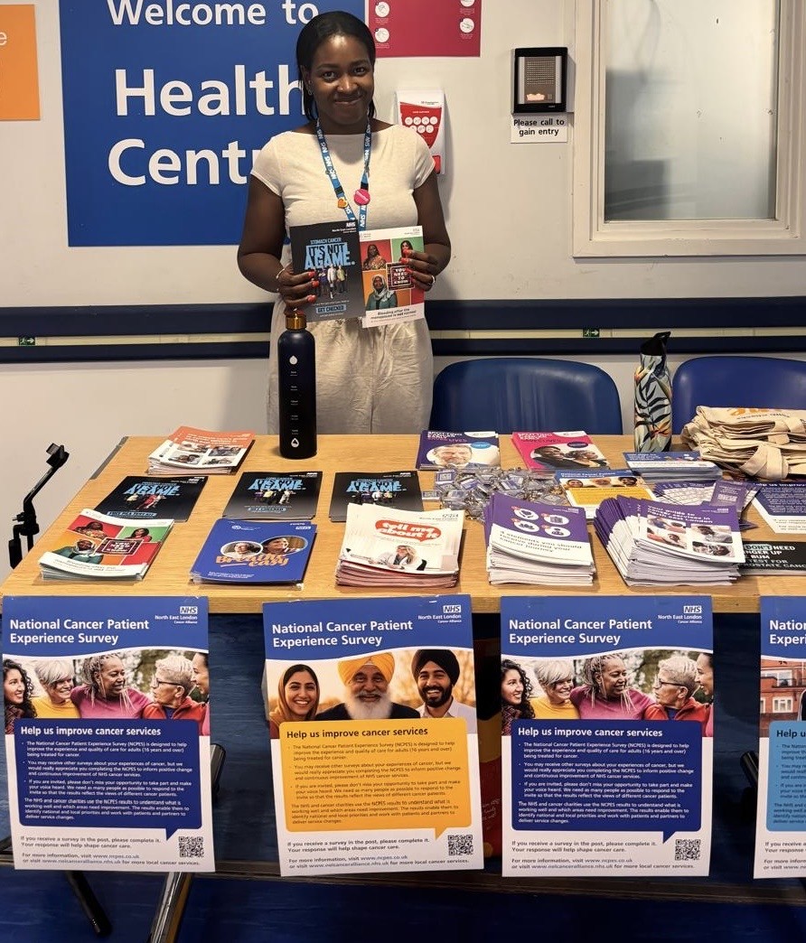 lady holding cancer leaflets behind a stall with flyers and informative materials