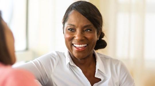 Middle aged person sat down smiling.