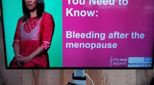 A TV screen has the words 'You Need to Know: Bleeding after the menopause' on it, alongside a woman in a red, asian dress