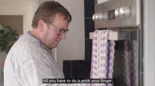 A man is standing in front of an oven. Below is a caption which says 'All you have to do is prick your finger'.