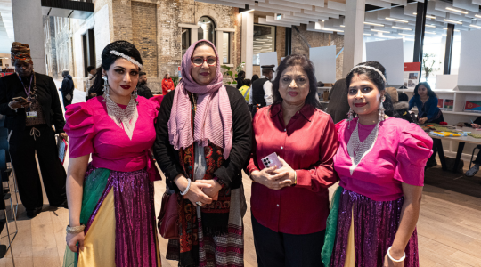 The image is of four women wearing pink outfits facing the camera