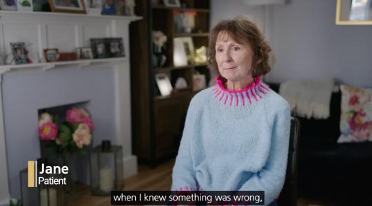 A lady in a grey jumper is sat in her home. Text in the bottom left corner says Jane, Patient. Text underneath her says When I knew something was wrong.