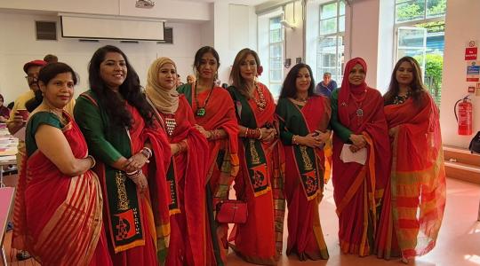 A group of 8 Bengali ladies all dressed in traditional red dress are standing together for a photo