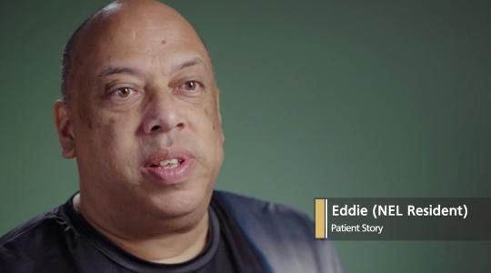 A man is facing the camera with a dark green background behind him. A caption says Eddie (NEL Resident) Patient Story.
