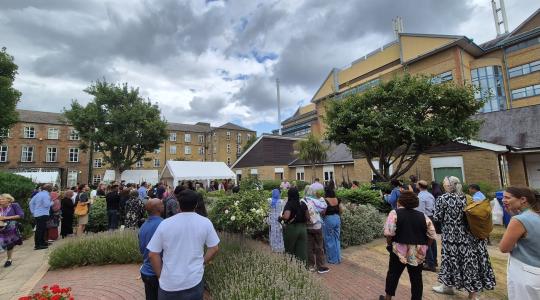 A large crowd of people are gathered outside at an event with grey skies overhead.