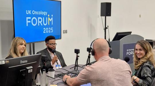 Four people are sat around a table recording a podcast in a room.
