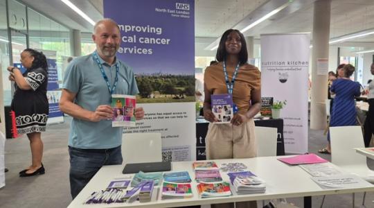 two people holding leaflets at a cancer awareness event