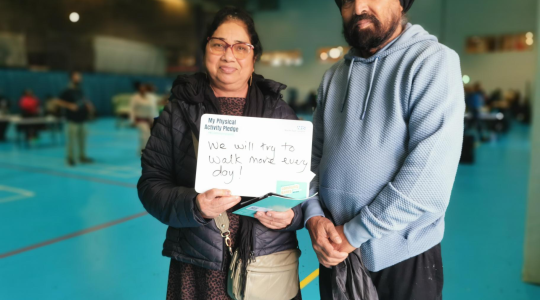 two people holding a whiteboard with a written pledge to walk more