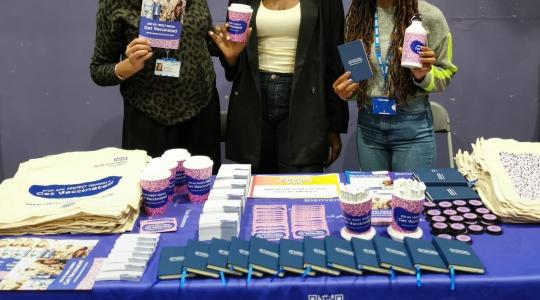 3 ladies standing behind a stand holding merch