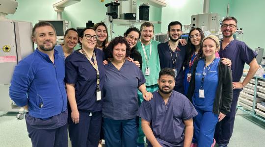 A team of clinicians in medical uniform is pictured in an operating theatre.