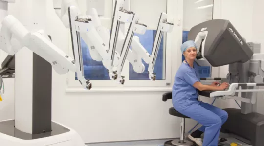 A clinician is operating robotic theatre in a hospital.