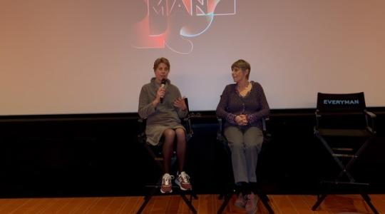 two women with a microphone in front of a movie screen 