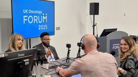 Four people are sat around a table recording a podcast in a room.