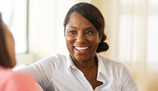 Middle aged person sat down smiling.