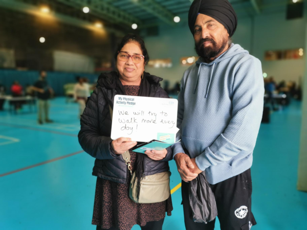 two people holding a whiteboard with a written pledge to walk more