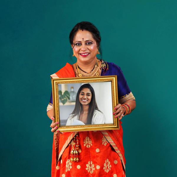 An asian woman is holding up a framed picture of her daughter.