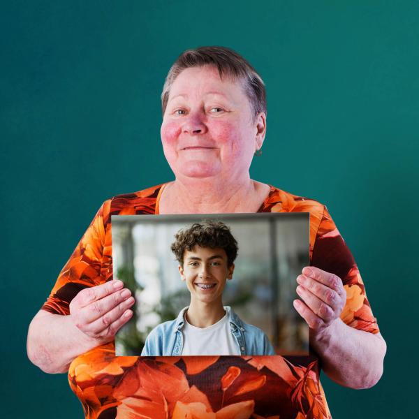 A lady is holding a framed photo of a younger man.